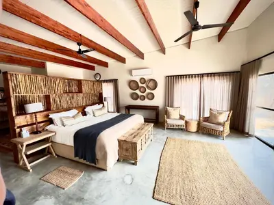 a bedroom with a large bed and a couch and chairs at Mananga Bush Villa in Skukuza