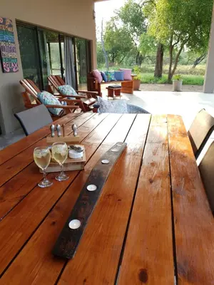 a wooden table with wine glasses on top of it at Mananga Bush Villa in Skukuza