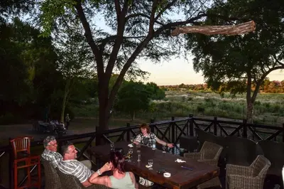 a group of people sitting at a table with drinks at Mananga Bush Villa in Skukuza