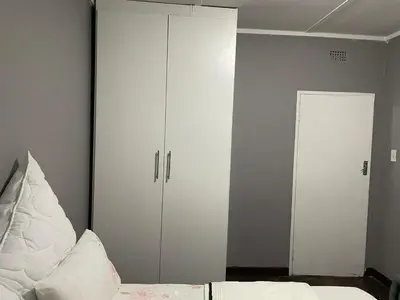 a bedroom with two white cabinets and a bed at White House in Kempton Park