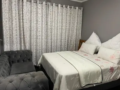 a bedroom with a bed and a chair and a window at White House in Kempton Park