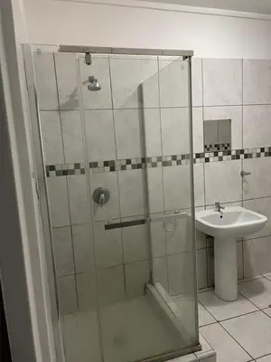 a shower with a glass door next to a sink at Torremolinos City in Kempton Park