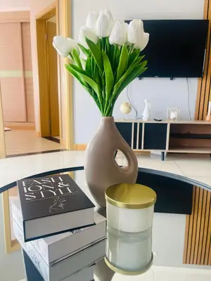 a vase with white flowers on a table with books at 12th La Maison in Erand