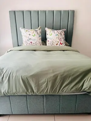a bed with a blue headboard and pillows at Tranquility in Erand