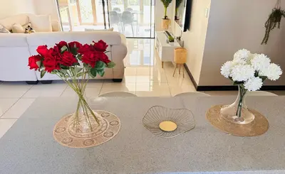 two vases with flowers on a table in a living room at Tranquility in Erand