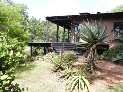 a house with a wooden porch with a large plant at DaGama Dam - White River - Kite - C11 in Swartfontein