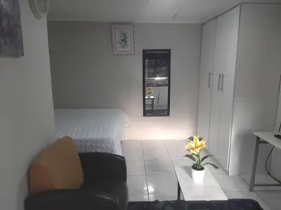 a bedroom with a bed and a chair and a table at Angel Secure Unit in Pretoria