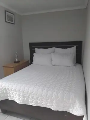 a bed with white sheets and pillows in a bedroom at Angel Secure Unit in Pretoria