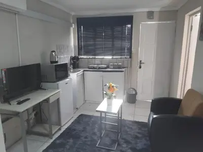 a small kitchen with a desk and a table with flowers at Angel Secure Unit in Pretoria
