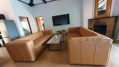 a living room with a brown leather couch and a tv at DaGama Dam - White River - Martial Eagle - C23 in Swartfontein