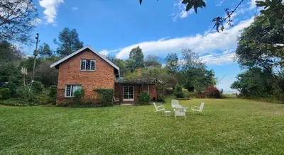 a brick house with white chairs in a yard at Country Cottage in Koppie Alleen