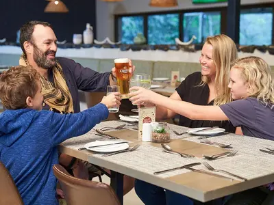 a family sitting at a table with a glass of beer at Hazyview Cabanas in Hazyview