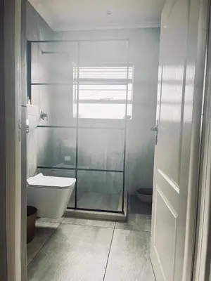 a bathroom with a glass shower and a toilet at Anga Spaces in Duvhapark