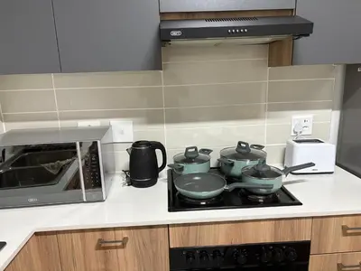 a kitchen with a stove with three pots and a microwave at Chaka at TheCreek in Pretoria