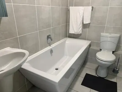 a bathroom with a toilet and a tub and a sink at Chaka at TheCreek in Pretoria