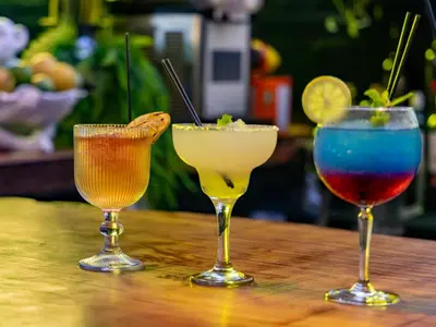 three cocktails sitting on a wooden table at Da Loose Mongoose in White River