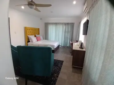 a hotel room with a bed and a chair at De Serene B&B in Midrand