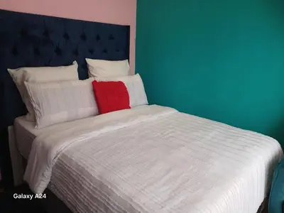 a bed with white sheets and a blue headboard at De Serene B&B in Midrand