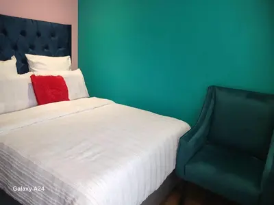 a bedroom with a bed with a red pillow and a chair at De Serene B&B in Midrand