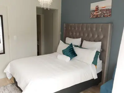 a bedroom with a large white bed with blue pillows at De Serene B&B in Midrand