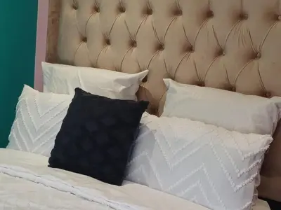 a bed with white pillows and a padded headboard at De Serene B&B in Midrand