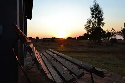 a park bench with the sunset in the background at Meadow Mist - Self Catering Unit in Dullstroom