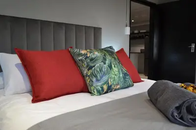 a bed with red and green pillows on it at Meadow Mist - Self Catering Unit in Dullstroom
