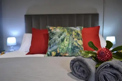 a bedroom with a bed with red pillows and a flower at Meadow Mist - Self Catering Unit in Dullstroom