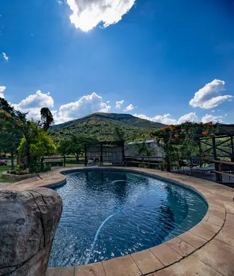 a swimming pool with a mountain in the background at Indabushe Eco Lodge in Schoemanskloof