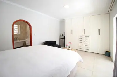 a white bedroom with a white bed and a mirror at honeymoon suite in Sandton