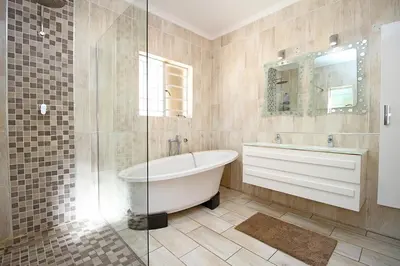 a bathroom with a tub and a glass shower at honeymoon suite in Sandton