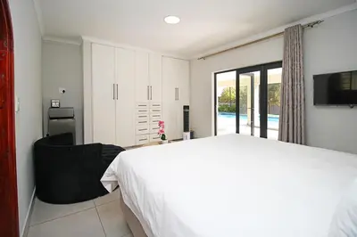a bedroom with a bed and a chair and a television at honeymoon suite in Sandton