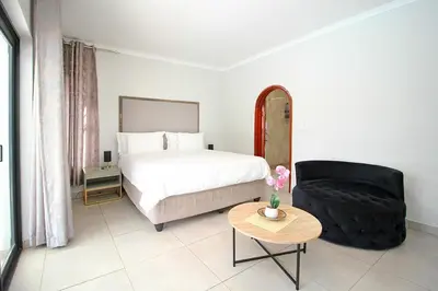 a bedroom with a bed and a chair and a table at honeymoon suite in Sandton