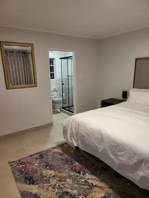 a bedroom with a bed and a mirror and a bathroom at Limewood super Deluxe in Sandton