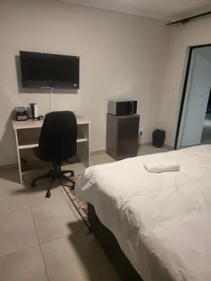 a bedroom with a bed and a desk and a chair at Limewood super Deluxe in Sandton