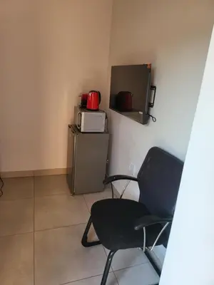 a room with a chair and a microwave and a refrigerator at Limewood Vintage in Sandton
