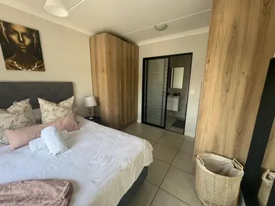 a bedroom with a large bed and a bathroom at The blyde in Pretoria
