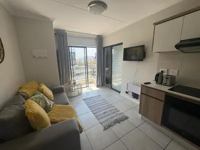 a living room with a couch and a kitchen at The blyde in Pretoria