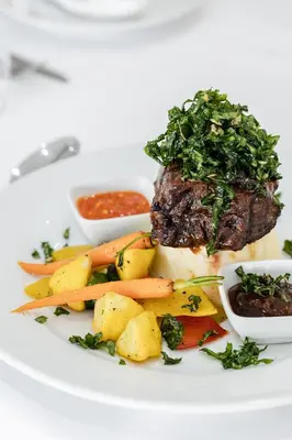 a plate of food with a piece of meat and vegetables at Point R40 Lodge - Conference, Self Catering & Spa in Nelspruit