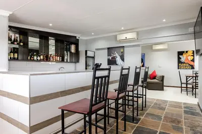 a bar in a hotel with chairs and a counter at Point R40 Lodge - Conference, Self Catering & Spa in Nelspruit