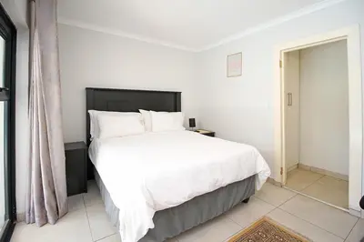a bedroom with a large bed with white sheets and pillows at Limewood in Sandton