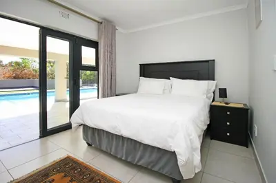 a bedroom with a large bed and a pool at Limewood in Sandton