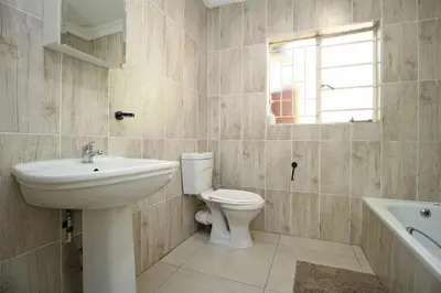 a bathroom with a sink and a toilet and a window at Limewood in Sandton