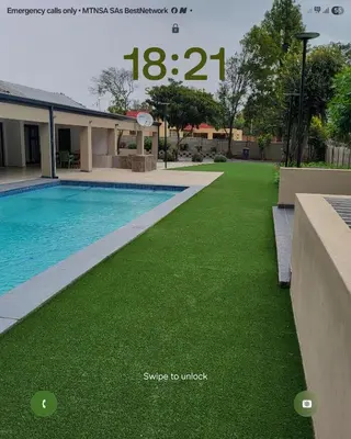 a swimming pool with green grass next to a house at Limewood in Sandton