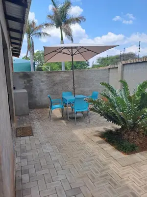 a patio with a table and chairs and an umbrella at Cycad Self Catering in Groblersdal