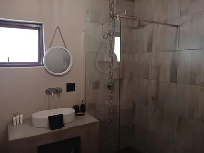 a bathroom with a shower and a sink and a mirror at Cycad Self Catering in Groblersdal