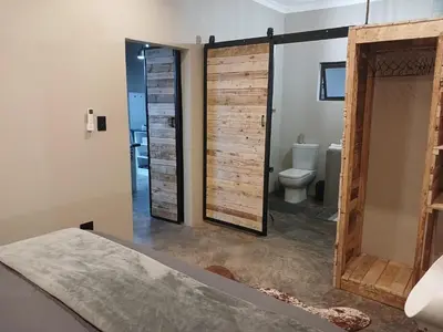 a bathroom with a sliding barn door and a toilet at Cycad Self Catering in Groblersdal