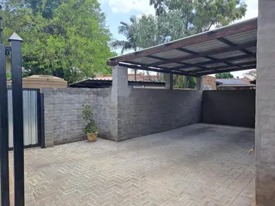 a patio with a stone wall and a wooden pergola at Cycad Self Catering in Groblersdal