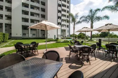 an outdoor patio with tables and chairs and umbrellas at Lovely 1 Bedroom Apartment in Pretoria