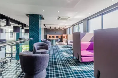 a waiting room with purple and pink chairs and tables at Lovely 1 Bedroom Apartment in Pretoria